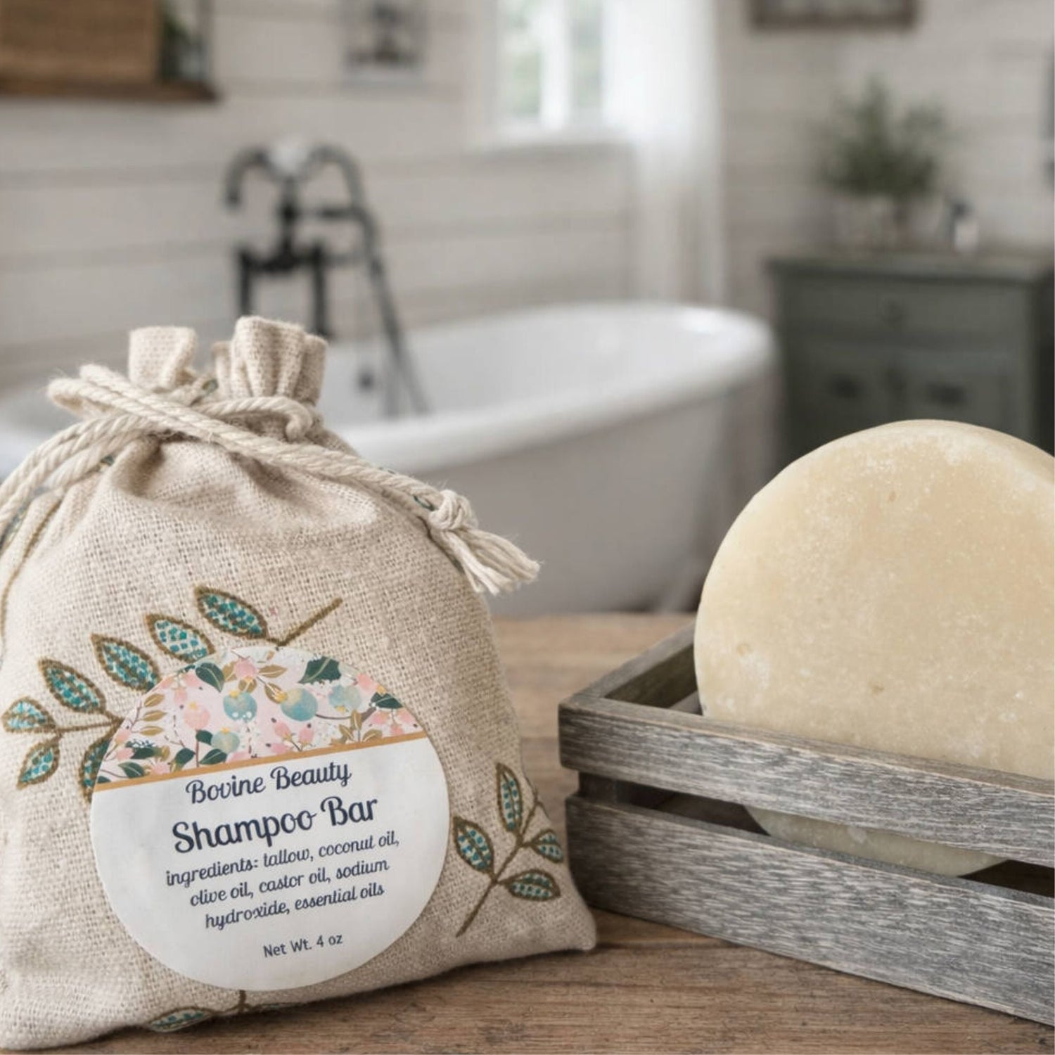 shampoo bar from bovine beauty tallow. one on bench in hessian bag with label, another in wooden soap tray and bathroom blurred in background
